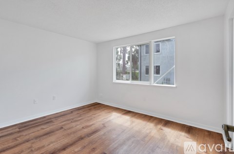 A room with wooden flooring and a window showing a building outside.