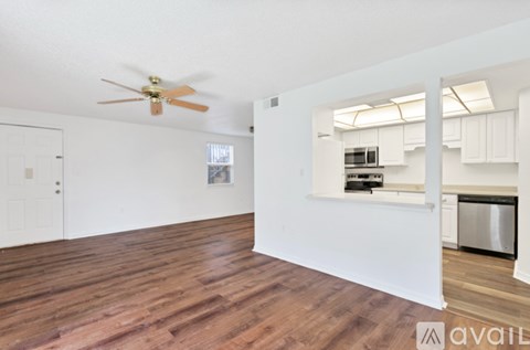 A spacious room with a ceiling fan and wooden flooring.