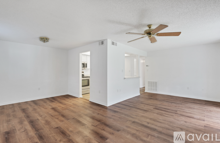 A room with a ceiling fan and wooden flooring.
