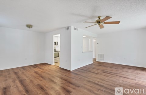 A room with a ceiling fan and wooden flooring.