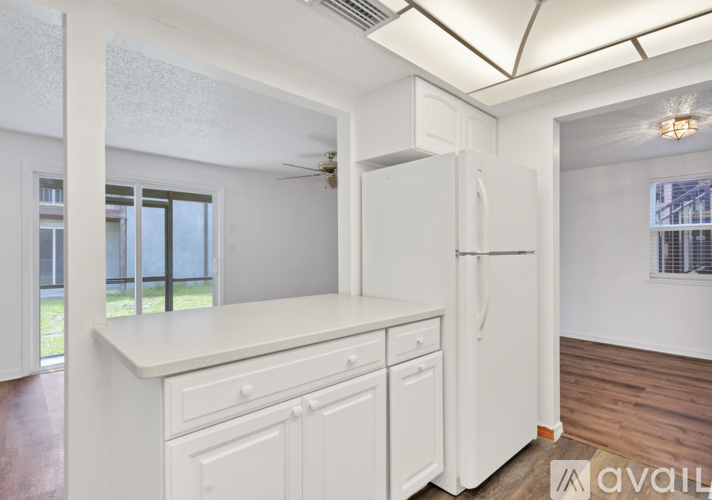 A kitchen with white cabinets and a white fridge.