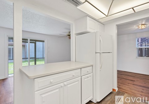 A kitchen with white cabinets and a white fridge.