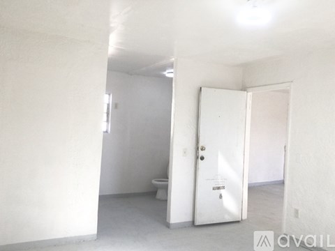 A white bathroom with a toilet and a door with a sign on it.