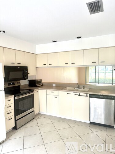 A kitchen with white cabinets and appliances.