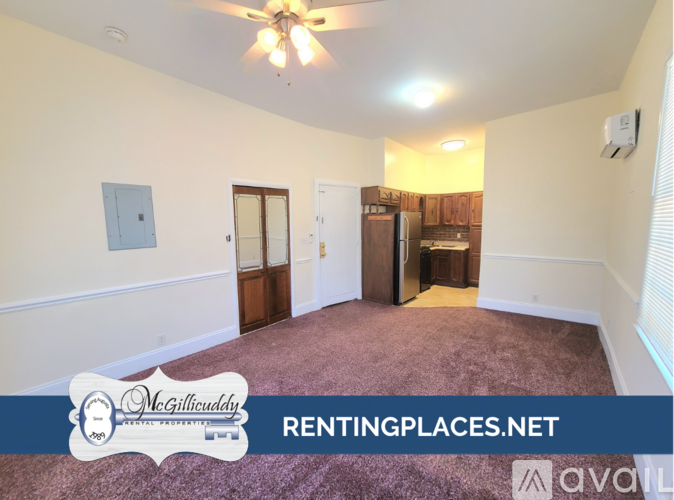 A room with a ceiling fan and a door leading to a kitchen.