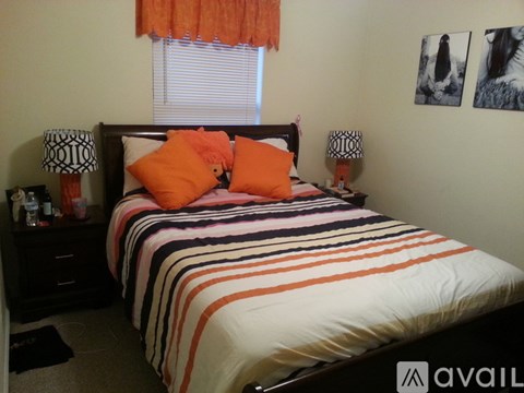 A bed with orange pillows and a striped comforter.