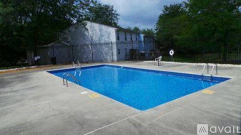 A blue swimming pool surrounded by a fence and trees.