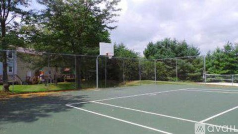 A basketball court surrounded by a fence and trees.