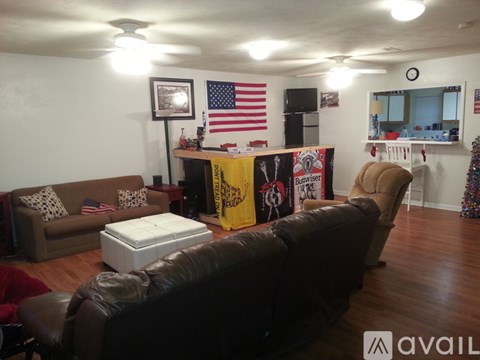 A living room with a brown couch, a white ottoman, and a yellow banner with the word "Budweiser" on it.