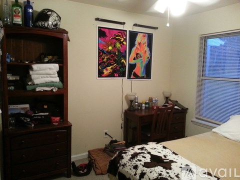 A bedroom with a bed, a dresser, a desk, and a painting on the wall.