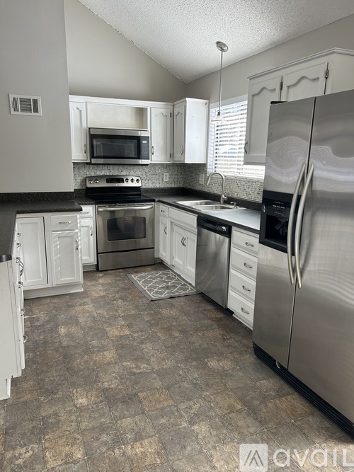 A kitchen with a tile floor and a stainless steel refrigerator.