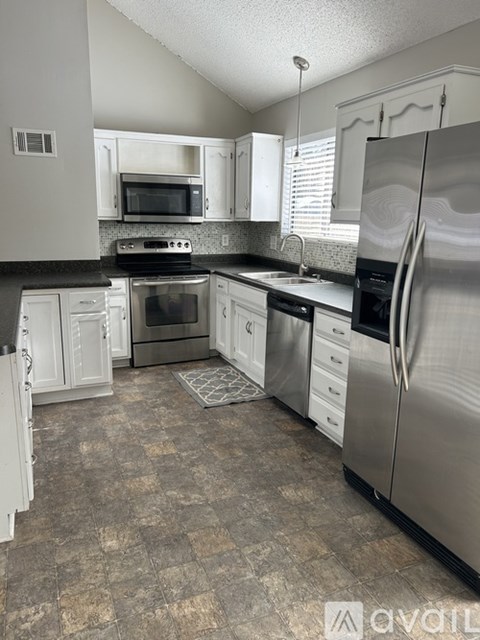 A kitchen with a tile floor and a stainless steel refrigerator.