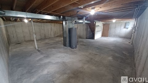 A spacious basement with a concrete floor and walls, a metal support beam, and a single light source.