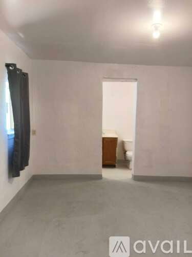 A room with a white wall and a black object hanging on it.