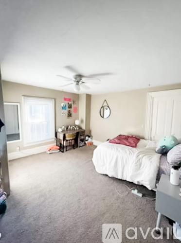 A bedroom with a white bed and a ceiling fan.