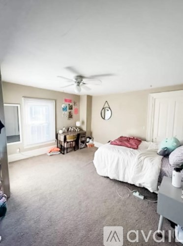 A bedroom with a white bed and a ceiling fan.