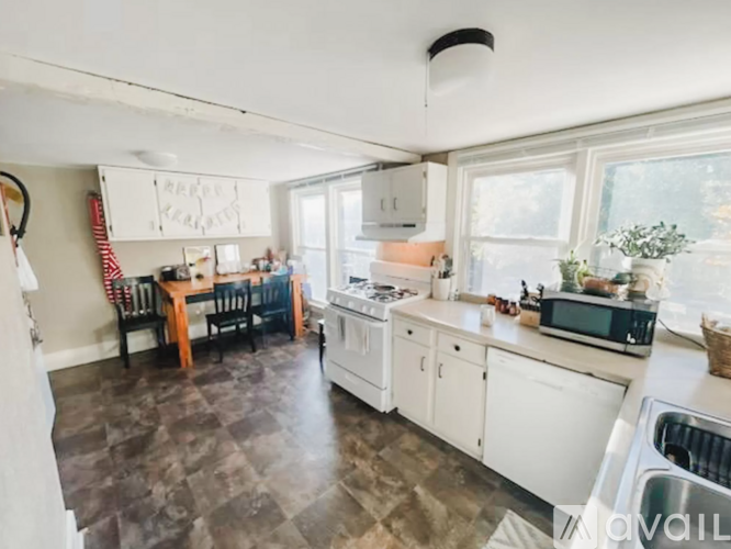 A kitchen with white cabinets and a darker floor.