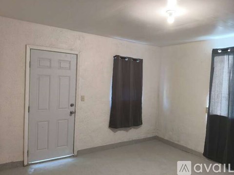 A room with a white door, a window with a brown curtain, and a black curtain on the right side.
