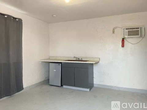 A room with a white countertop, a grey cabinet, and a fire extinguisher on the wall.