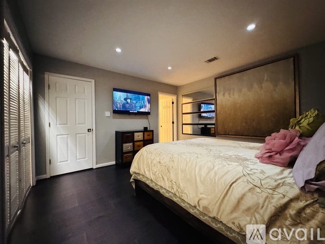 A bedroom with a bed, a dresser, and a television.