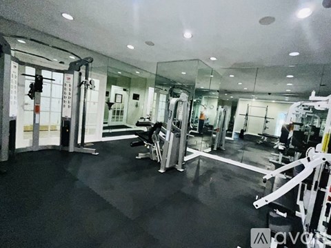 A gym with a variety of equipment including a squat rack, a bench press, and a leg press machine.