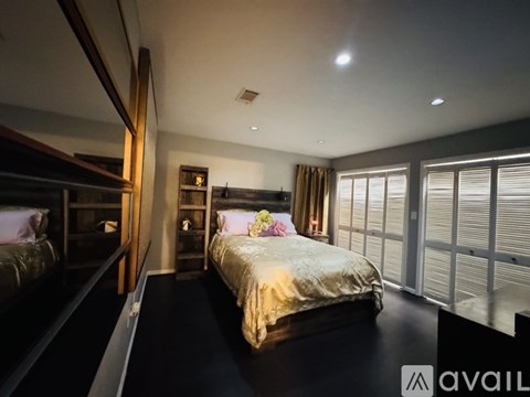 A bedroom with a large bed and a window with blinds.