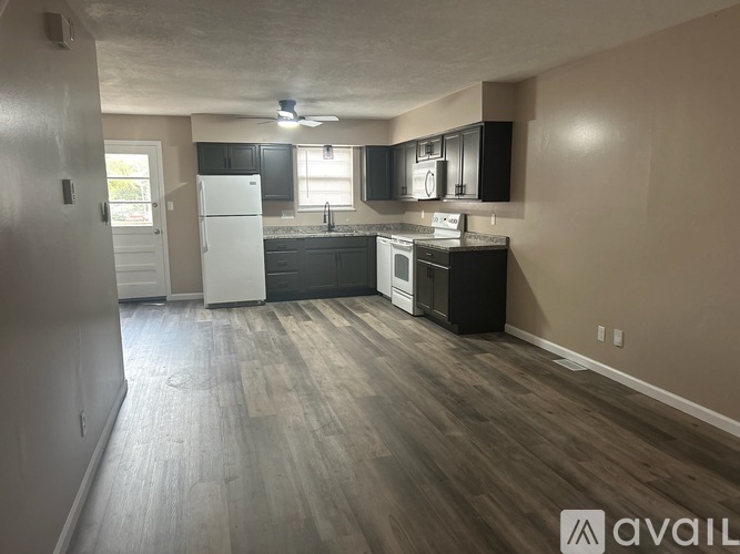 A kitchen with a white refrigerator and black cabinets.