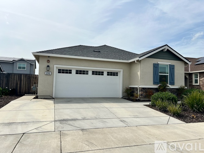 A two-car garage is attached to a house with a white door and blue shutters.
