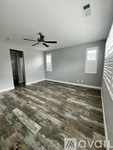 A room with a ceiling fan and wood flooring.