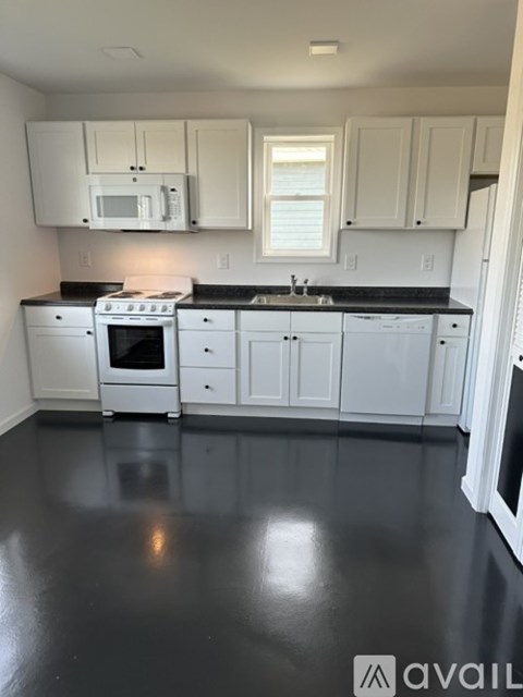 A kitchen with white cabinets and black countertops.