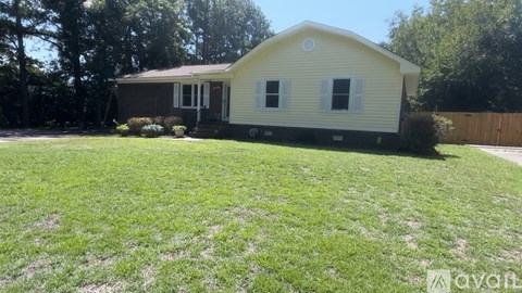 A yellow house with a white door and windows is surrounded by a green lawn.