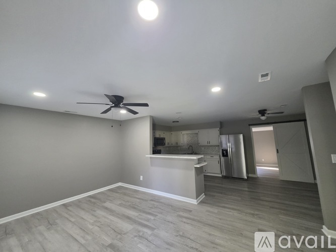 A spacious kitchen and living room with a ceiling fan and recessed lighting.