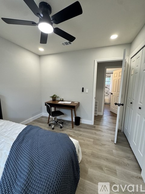 A bedroom with a bed, desk, and chair.