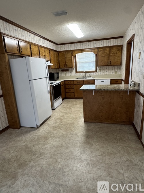 A kitchen with a white refrigerator and wooden cabinets.