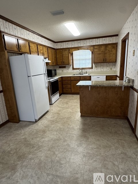 A kitchen with a white refrigerator and wooden cabinets.