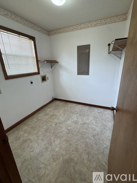 A room with a window, a shelf, and a light switch.