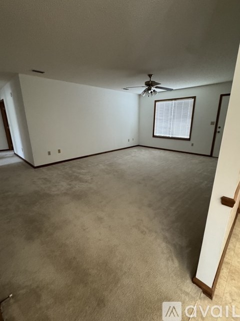 A spacious room with a ceiling fan and a window with blinds.