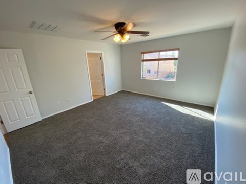 A room with a ceiling fan and a window with a view of a building outside.