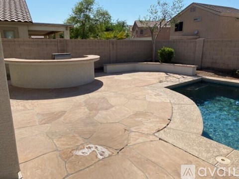 A pool with a stone patio and a hot tub.