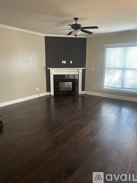 A living room with a fireplace and a ceiling fan.