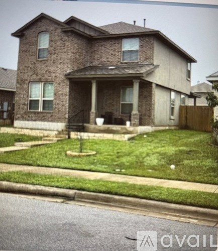 A house with a brown brick exterior and a front yard with a small tree.