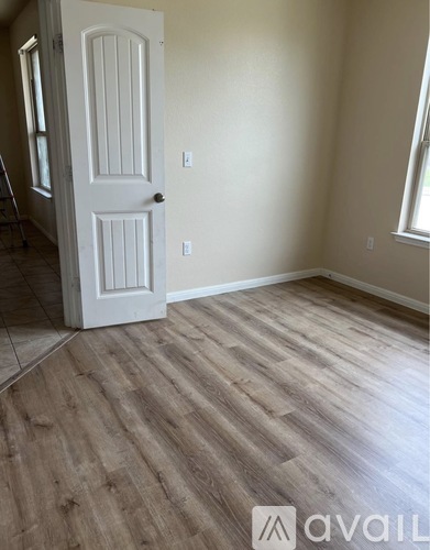 A room with a white door and wooden flooring.
