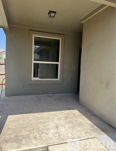 A concrete patio area with a window and a door.