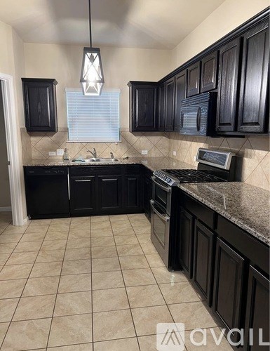 A kitchen with black cabinets and a granite countertop.