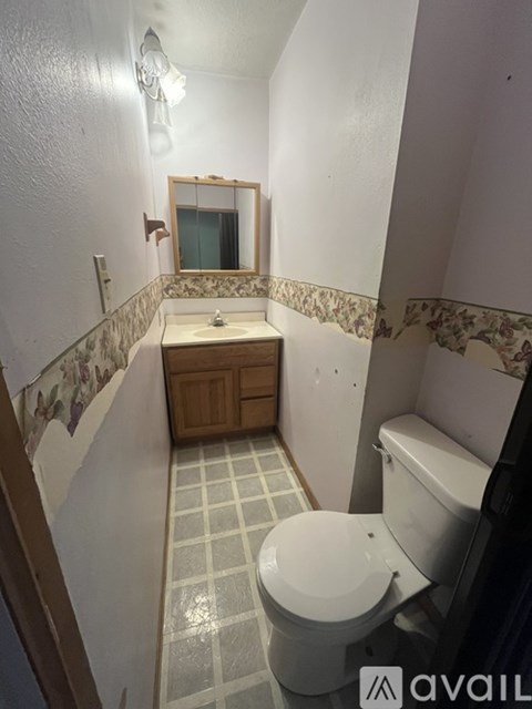 A bathroom with a toilet, sink, and mirror.