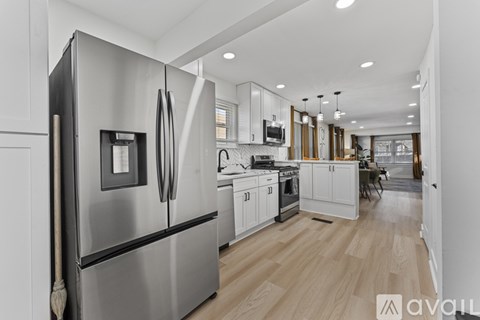 A modern kitchen with a stainless steel refrigerator and wooden flooring.