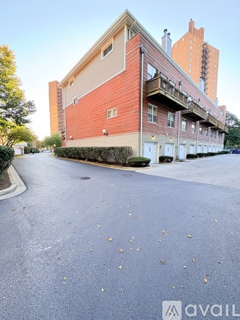 A street view of a building with a red brick facade and a balcony on the second floor.