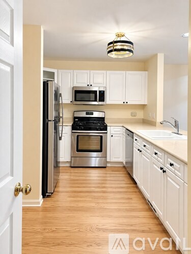 A kitchen with white cabinets and a black fridge.