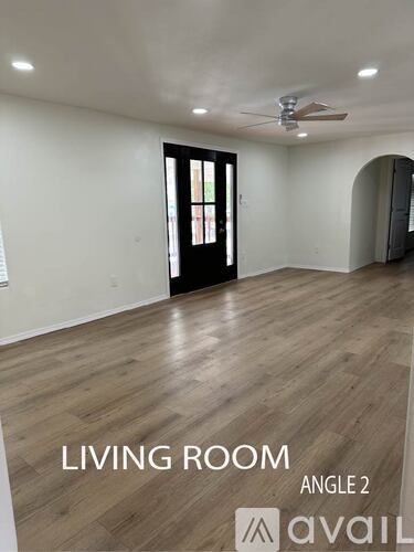 A living room with wood flooring and a ceiling fan.