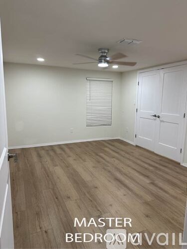 A master bedroom with a wooden floor and white walls.
